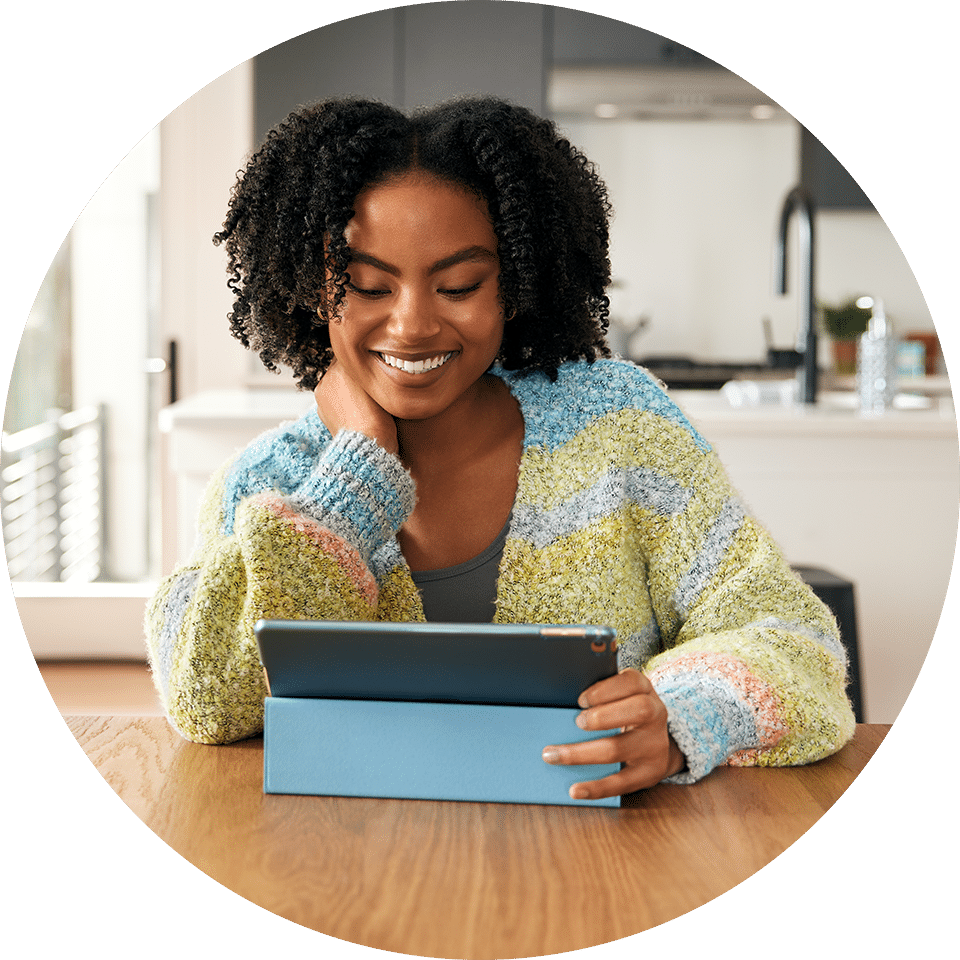 Teenaged girl watching Tablo on her tablet in the kitchen