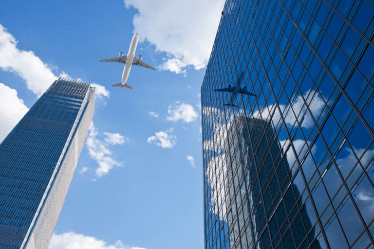 Jumbo jet flying over a sky scrapper and office building.