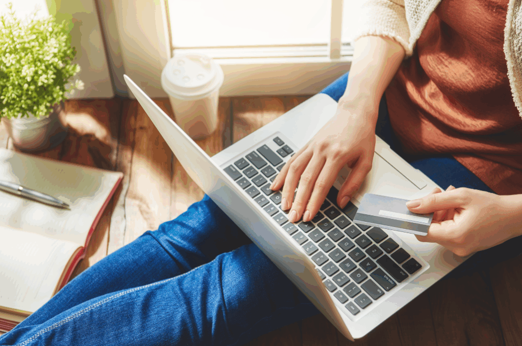Laptop in a woman's lap, she's holding a credit card.